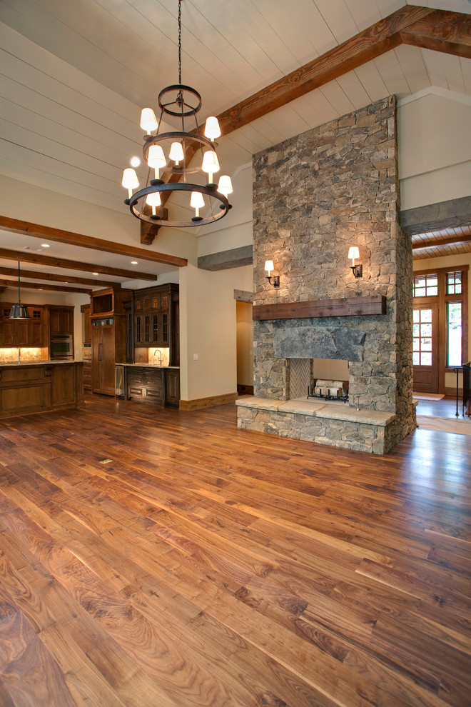 Photo of a large traditional open plan living room in Atlanta with medium hardwood flooring, a stone fireplace surround, beige walls, a two-sided fireplace and brown floors.