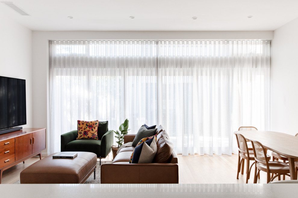Imagen de salón abierto contemporáneo de tamaño medio con paredes blancas, suelo de madera clara, televisor colgado en la pared y suelo beige