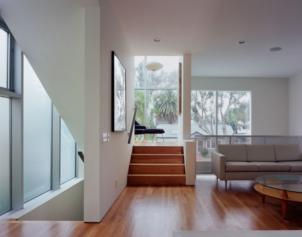 Idée de décoration pour un salon minimaliste ouvert avec un mur blanc et un escalier.