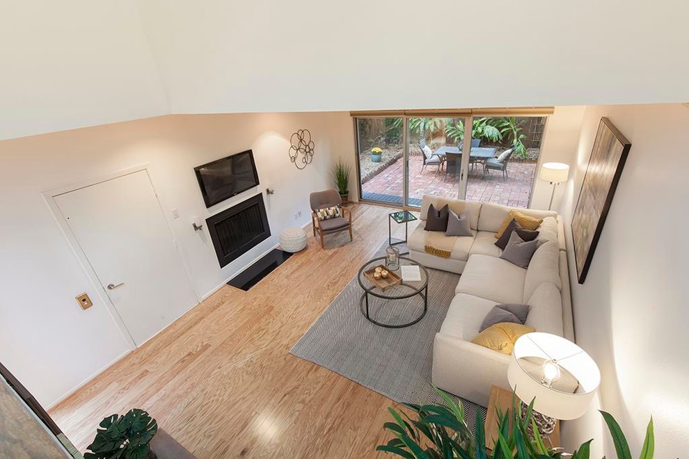 Пример оригинального дизайна: гостиная комната в стиле ретро с белыми стенами, стандартным камином, фасадом камина из металла и телевизором на стене