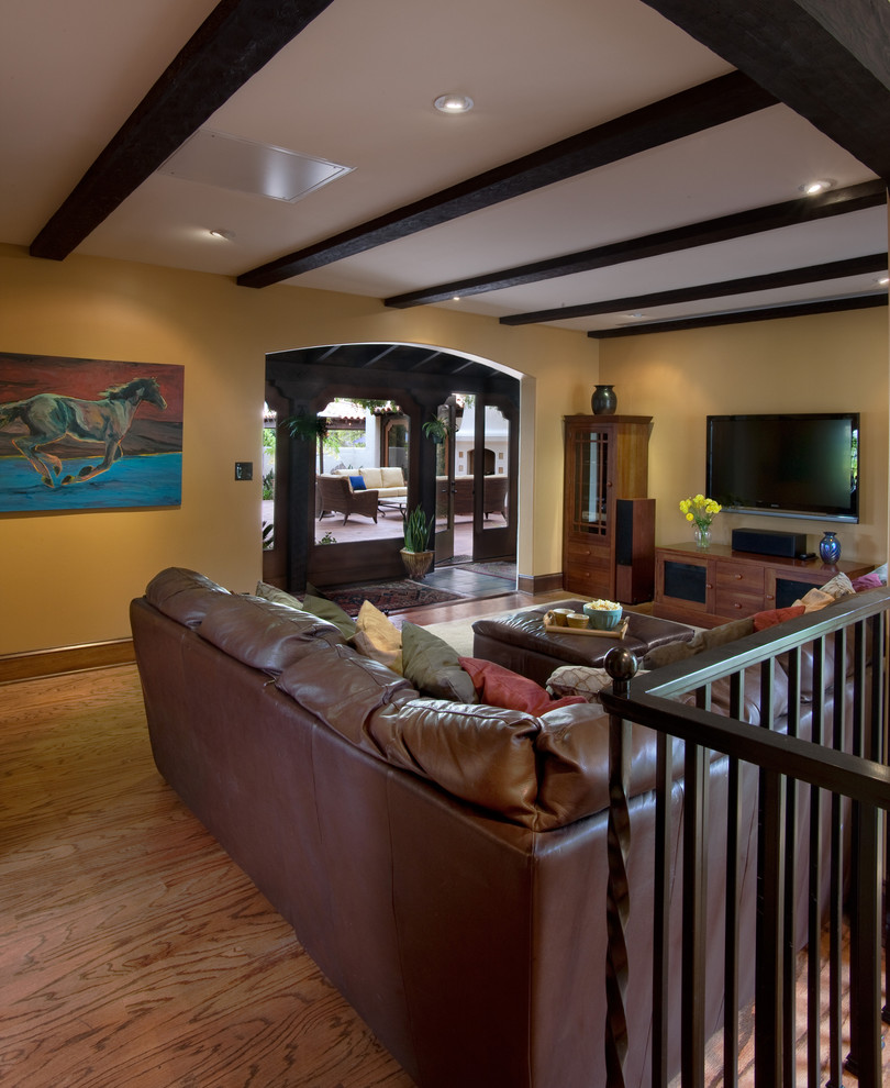Foto di un soggiorno mediterraneo con pareti beige, pavimento in legno massello medio e TV a parete
