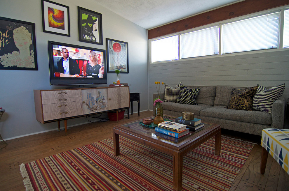 Foto på ett 60 tals vardagsrum, med grå väggar, mellanmörkt trägolv och en fristående TV