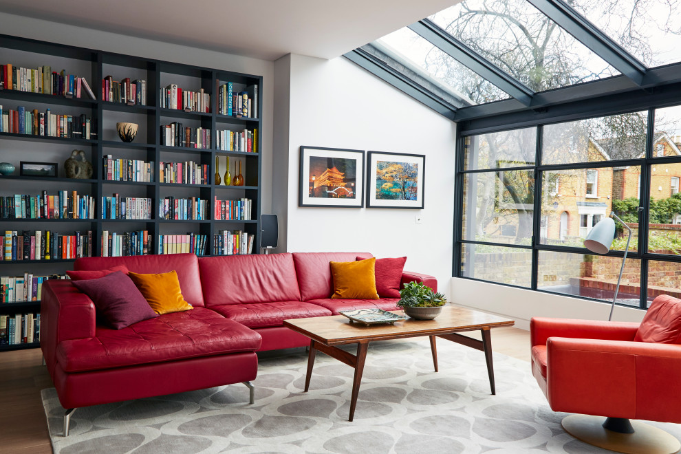 Photo of a contemporary living room in London with a reading nook, white walls, medium hardwood flooring, brown floors and a vaulted ceiling.