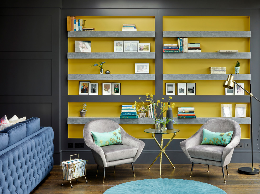 This is an example of a large classic grey and yellow open plan living room in London with a reading nook, black walls and dark hardwood flooring.