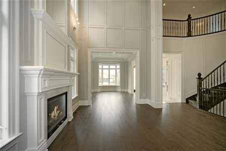 Пример оригинального дизайна: гостиная комната в стиле неоклассика (современная классика) с белыми стенами, темным паркетным полом, стандартным камином и фасадом камина из дерева без телевизора