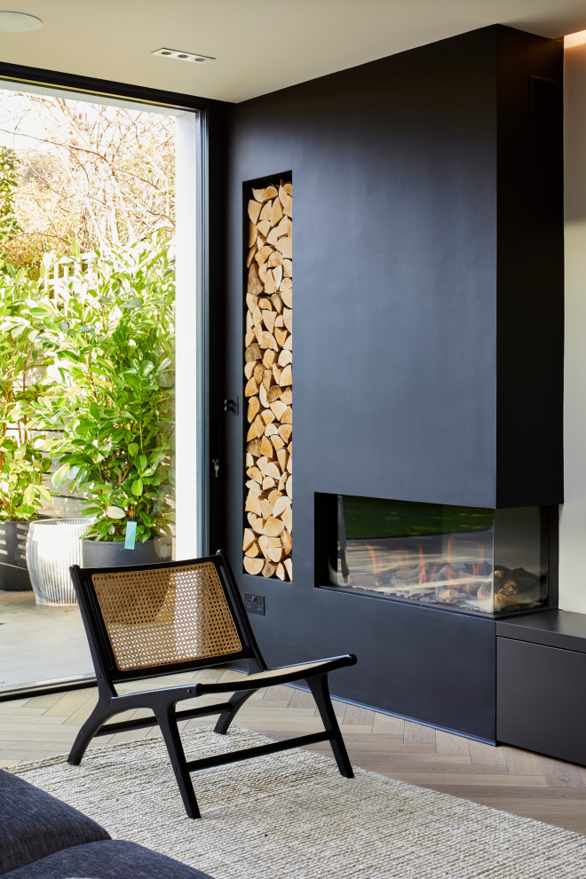Diseño de salón contemporáneo con paredes negras, suelo de madera clara, chimenea de esquina y marco de chimenea de yeso