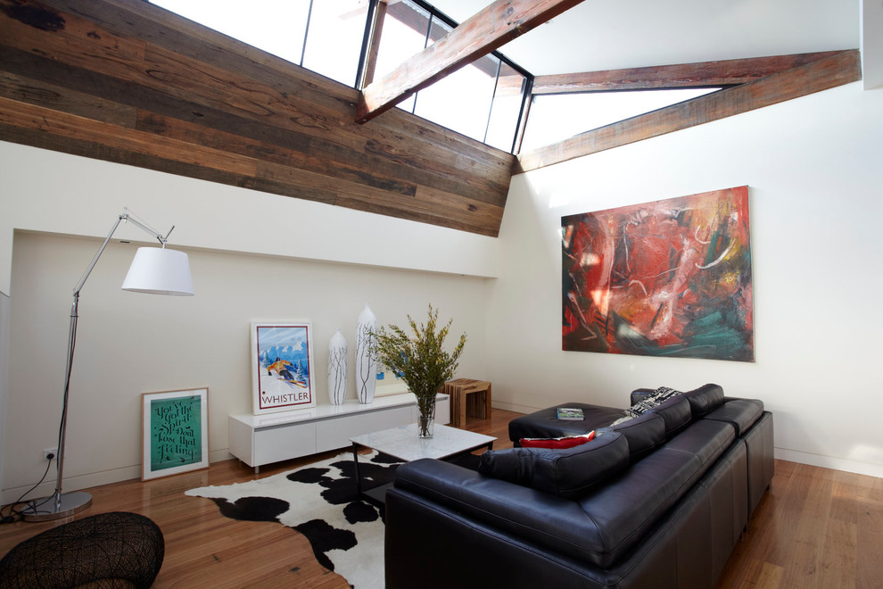 This is an example of an urban living room in Melbourne with white walls, light hardwood flooring and no fireplace.