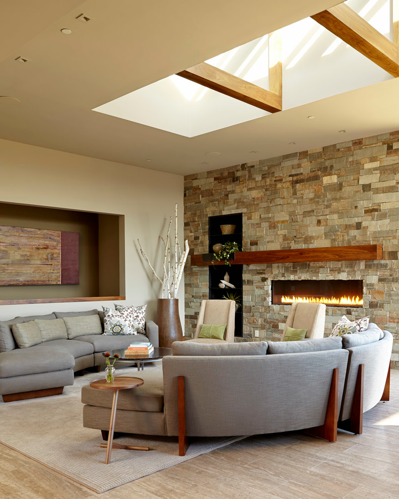 Пример оригинального дизайна: большая открытая гостиная комната в современном стиле с горизонтальным камином, фасадом камина из камня, бежевыми стенами, светлым паркетным полом, телевизором на стене, серым полом и ковром на полу