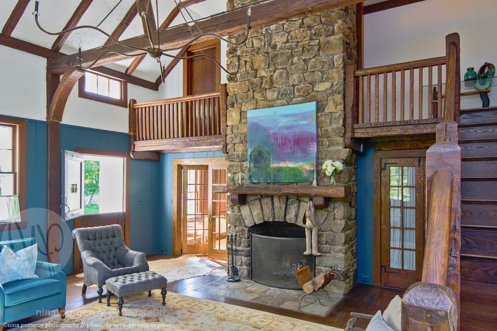 Пример оригинального дизайна: огромная открытая гостиная комната в стиле кантри с синими стенами, темным паркетным полом, стандартным камином и фасадом камина из камня