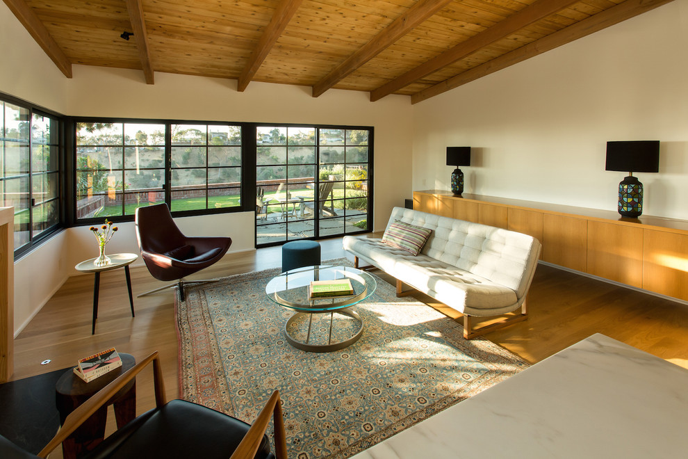 Пример оригинального дизайна: большая открытая гостиная комната в стиле ретро с белыми стенами, светлым паркетным полом, стандартным камином, фасадом камина из штукатурки и желтым полом без телевизора