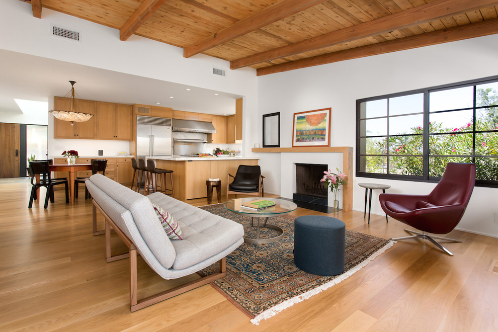 Mittelgroßes, Fernseherloses, Offenes Mid-Century Wohnzimmer mit weißer Wandfarbe, hellem Holzboden, Kamin, verputzter Kaminumrandung und gelbem Boden in Los Angeles