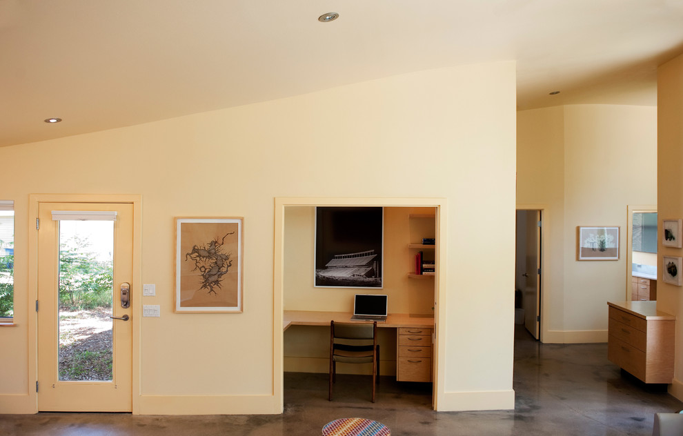 Imagen de salón para visitas abierto contemporáneo de tamaño medio con suelo de cemento, pared multimedia y paredes amarillas