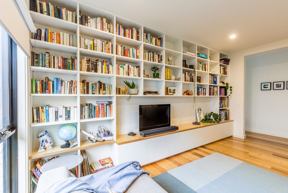 Aménagement d'un grand salon contemporain fermé avec un mur blanc, un sol en bois brun, aucune cheminée, un téléviseur indépendant, une bibliothèque ou un coin lecture et un sol marron.