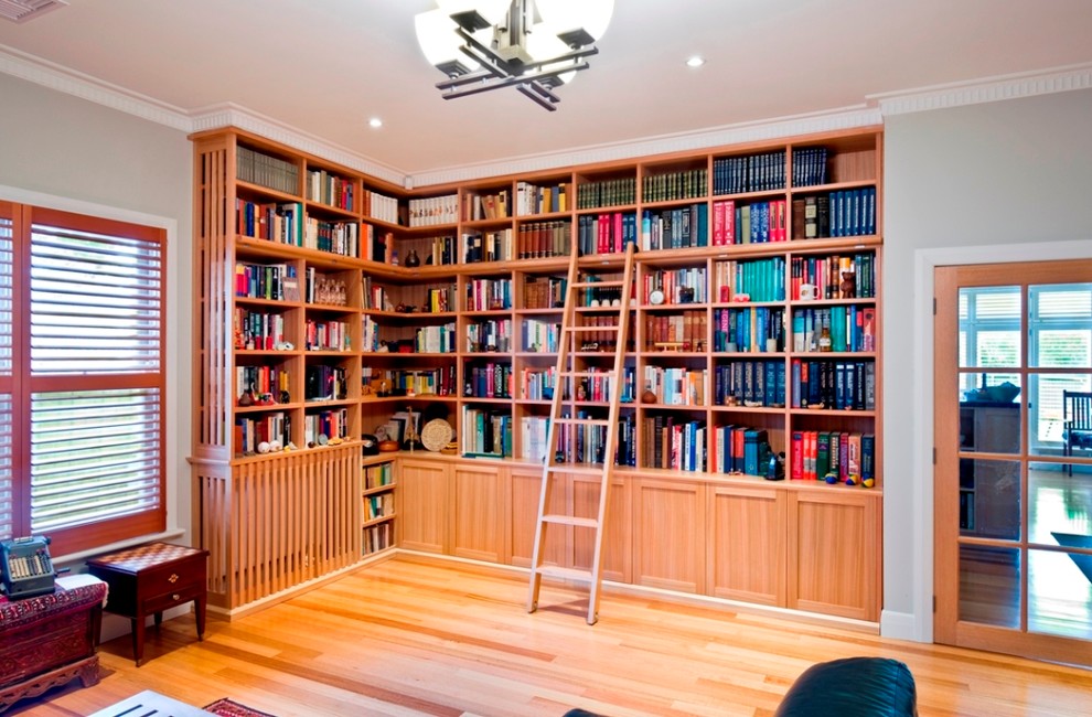 Immagine di un grande soggiorno chic aperto con libreria, pareti beige, parquet chiaro, nessun camino e nessuna TV