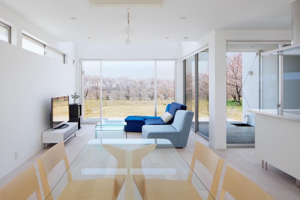 Offenes Modernes Wohnzimmer mit weißer Wandfarbe, freistehendem TV und beigem Boden in Sonstige