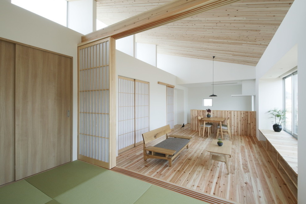 Photo of a small world-inspired open plan living room in Other with white walls, light hardwood flooring, a freestanding tv and beige floors.