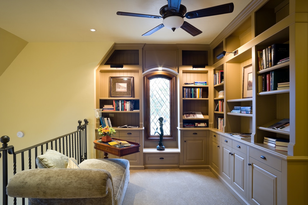 Пример оригинального дизайна: маленькая двухуровневая гостиная комната в классическом стиле с с книжными шкафами и полками, желтыми стенами, ковровым покрытием и бежевым полом без камина, телевизора для на участке и в саду