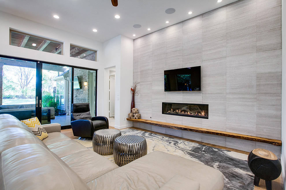 Inspiration for a large contemporary formal open plan living room in Dallas with white walls, light hardwood flooring, a ribbon fireplace, a tiled fireplace surround and a wall mounted tv.