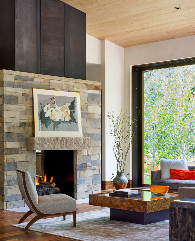 Example of a trendy open concept medium tone wood floor living room design in Denver with white walls, a standard fireplace, a stone fireplace and no tv