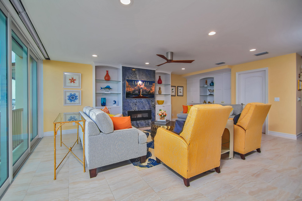 Идея дизайна: открытая гостиная комната среднего размера в морском стиле с желтыми стенами, полом из керамогранита, горизонтальным камином, фасадом камина из камня и телевизором на стене