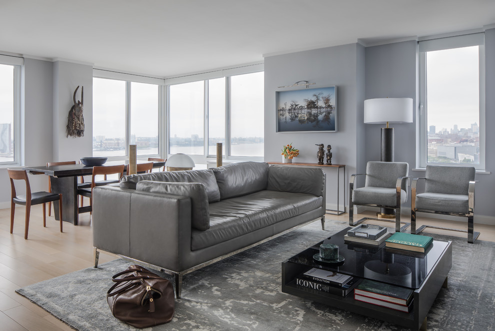 This is an example of a contemporary open plan living room in New York with grey walls, light hardwood flooring and beige floors.
