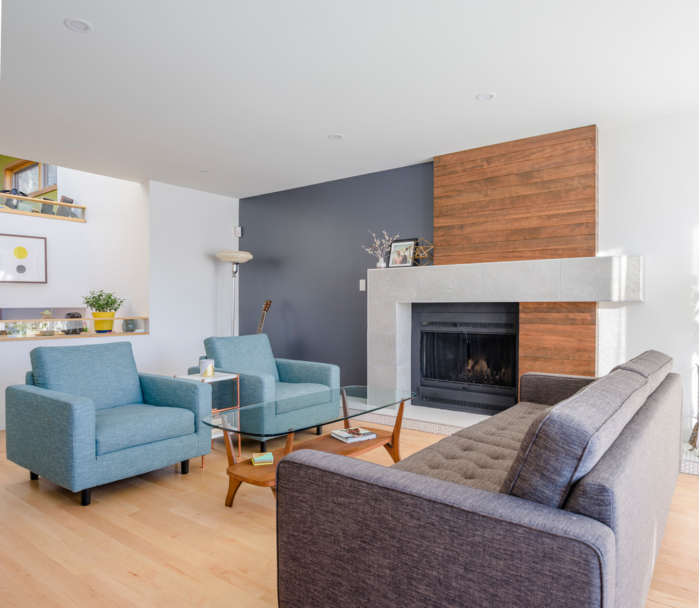 Contemporary open plan living room in Calgary with grey walls, light hardwood flooring, a standard fireplace, a metal fireplace surround and beige floors.