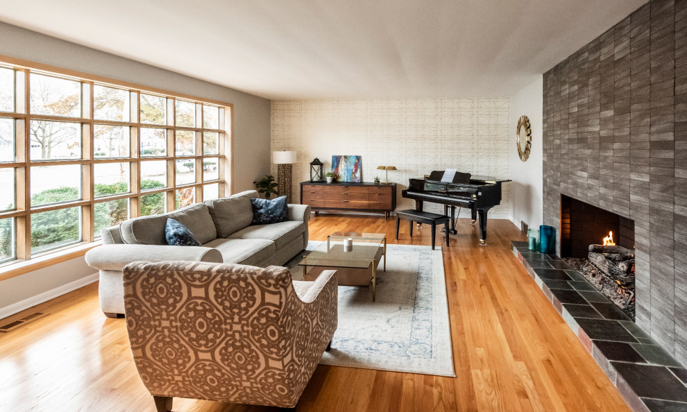 Example of a large 1950s open concept medium tone wood floor and brown floor living room design in Chicago with a music area, gray walls, a standard fireplace, a tile fireplace and no tv
