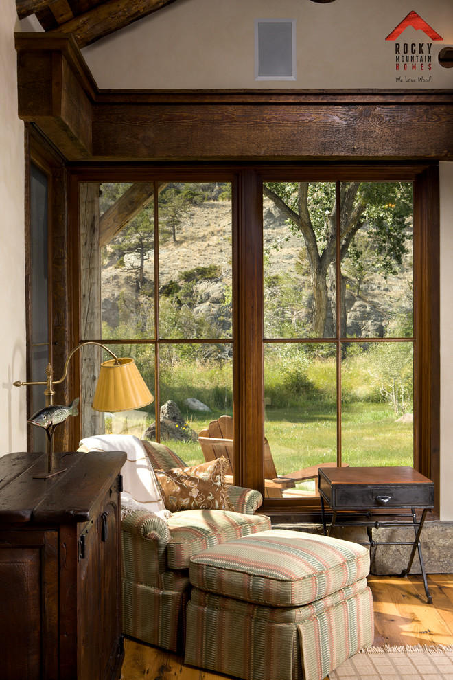 Imagen de salón abierto rural de tamaño medio con paredes beige, suelo de madera clara, chimenea de doble cara y marco de chimenea de piedra