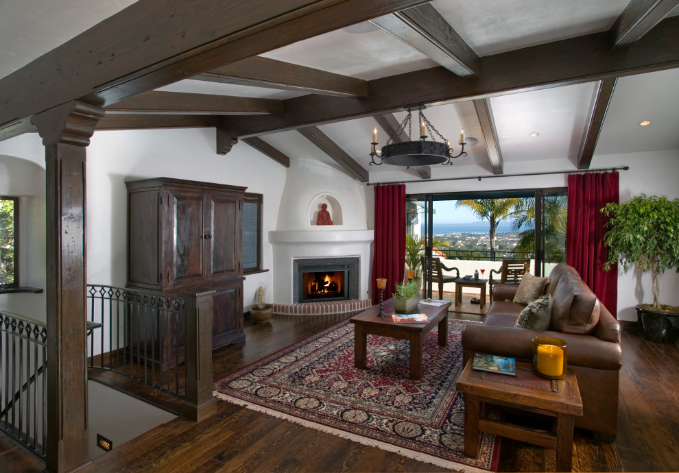 Mittelgroßes Mediterranes Wohnzimmer mit weißer Wandfarbe, braunem Holzboden, Eckkamin, verputzter Kaminumrandung, braunem Boden und gewölbter Decke in Santa Barbara