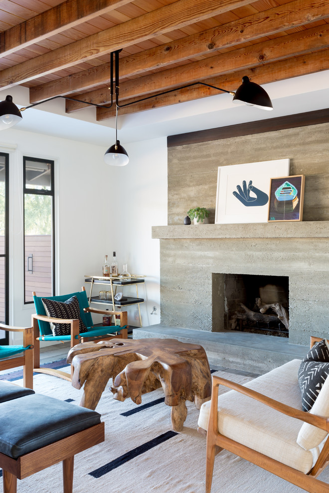 This is an example of a contemporary living room in Orange County with white walls, a standard fireplace and a concrete fireplace surround.