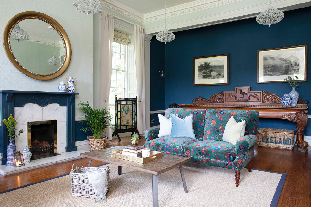 Bild på ett vintage vardagsrum, med blå väggar, mörkt trägolv, en standard öppen spis, en spiselkrans i sten och brunt golv