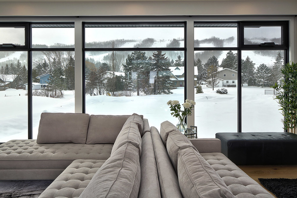 Immagine di un grande soggiorno minimalista aperto con pareti grigie, parquet chiaro, parete attrezzata e pavimento beige