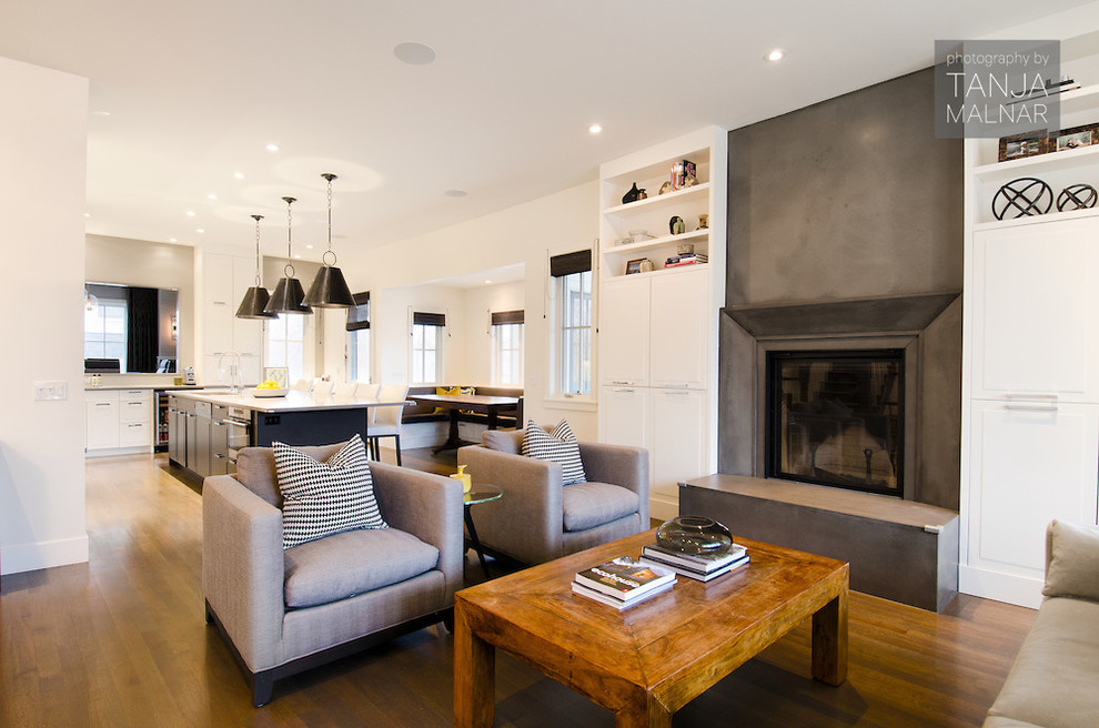 Großes, Fernseherloses, Offenes Modernes Wohnzimmer mit beiger Wandfarbe, braunem Holzboden, Kamin und Kaminumrandung aus Beton in Calgary