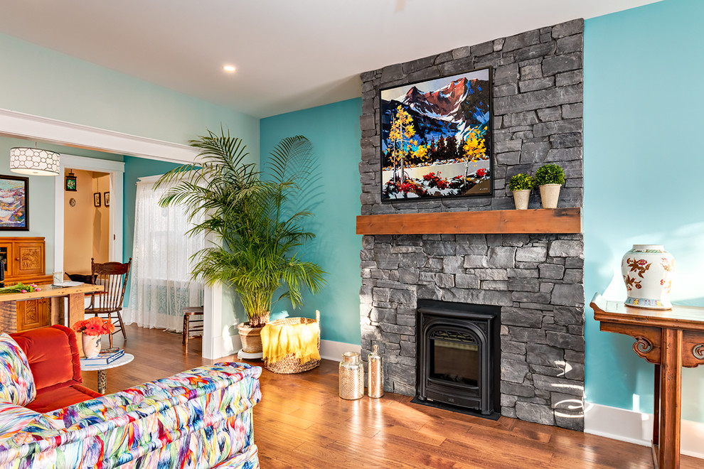 Foto de salón cerrado romántico pequeño con paredes azules, suelo de madera en tonos medios, estufa de leña, marco de chimenea de piedra y suelo marrón