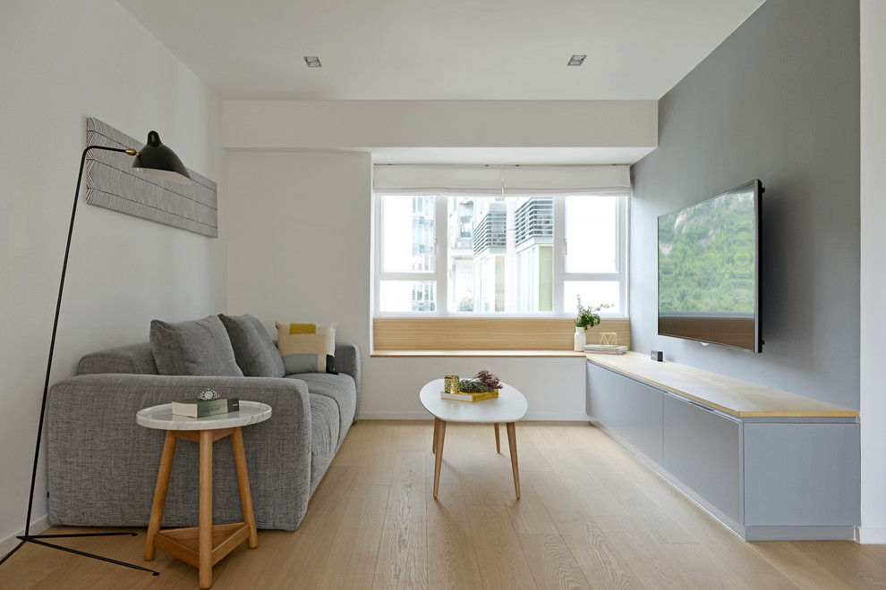 Nordisk inredning av ett vardagsrum, med grå väggar, ljust trägolv och en väggmonterad TV