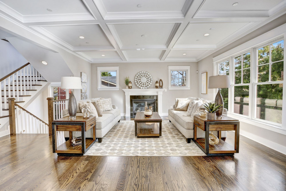 Large traditional formal open plan living room in DC Metro with grey walls, medium hardwood flooring, a standard fireplace, a tiled fireplace surround, no tv, brown floors and a coffered ceiling.