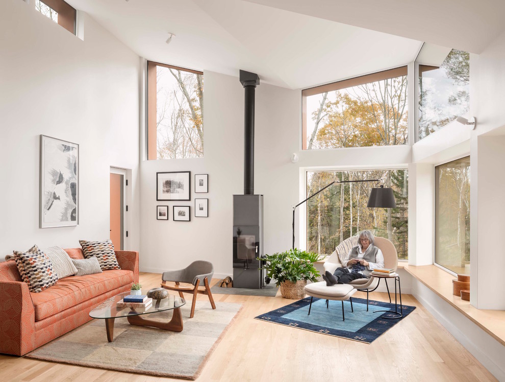 Offenes Modernes Wohnzimmer mit weißer Wandfarbe, hellem Holzboden, Kaminofen und beigem Boden in Sonstige