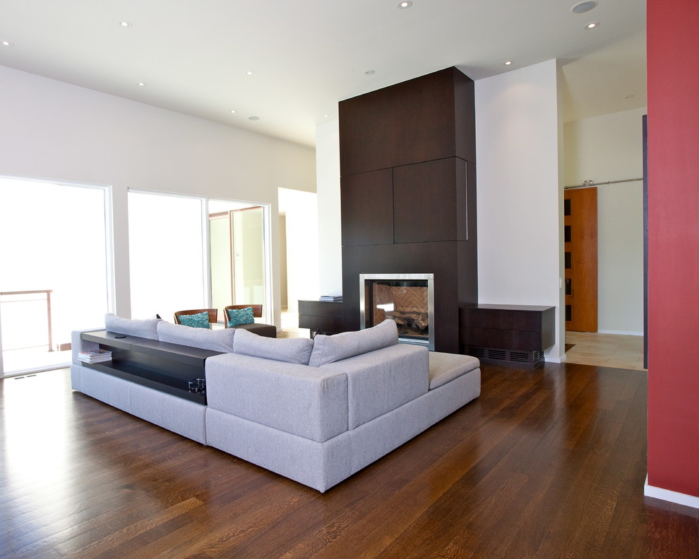 Imagen de salón abierto minimalista con paredes multicolor, suelo de madera en tonos medios, todas las chimeneas, marco de chimenea de madera y televisor retractable