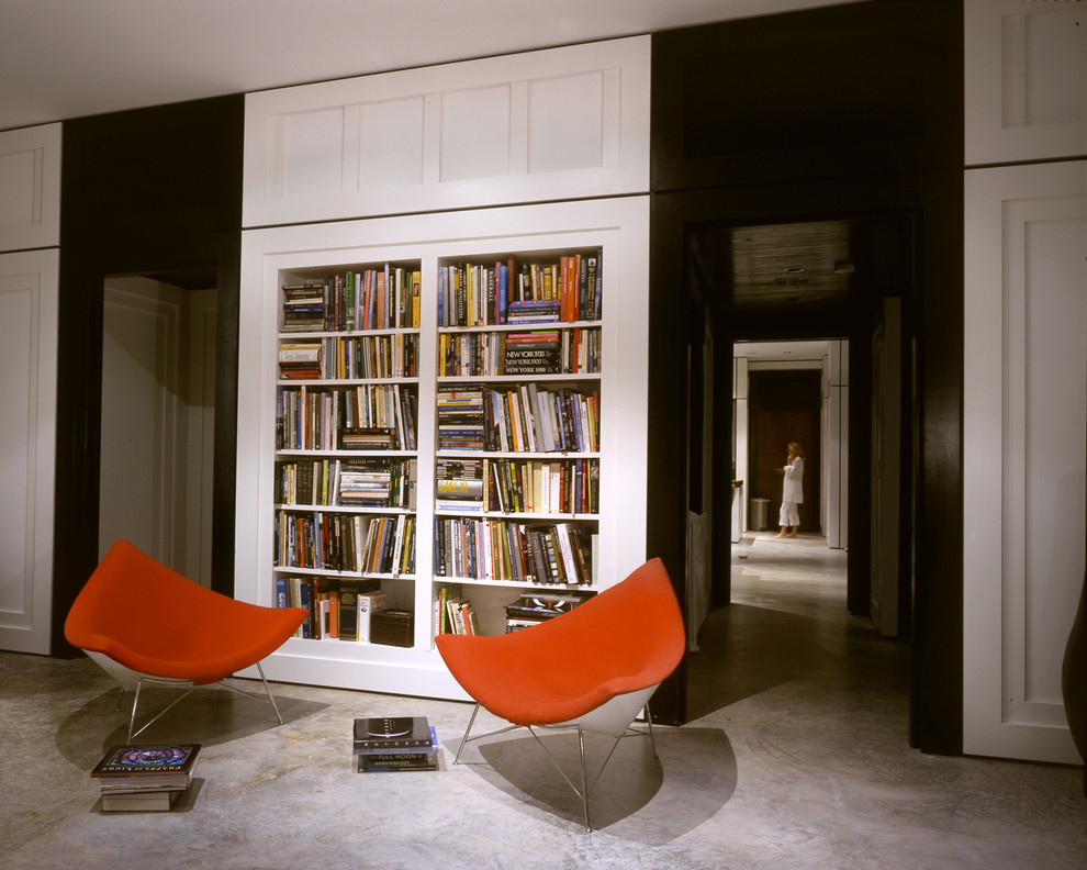 На фото: изолированная гостиная комната среднего размера в современном стиле с бетонным полом, с книжными шкафами и полками, белыми стенами и серым полом без камина, телевизора