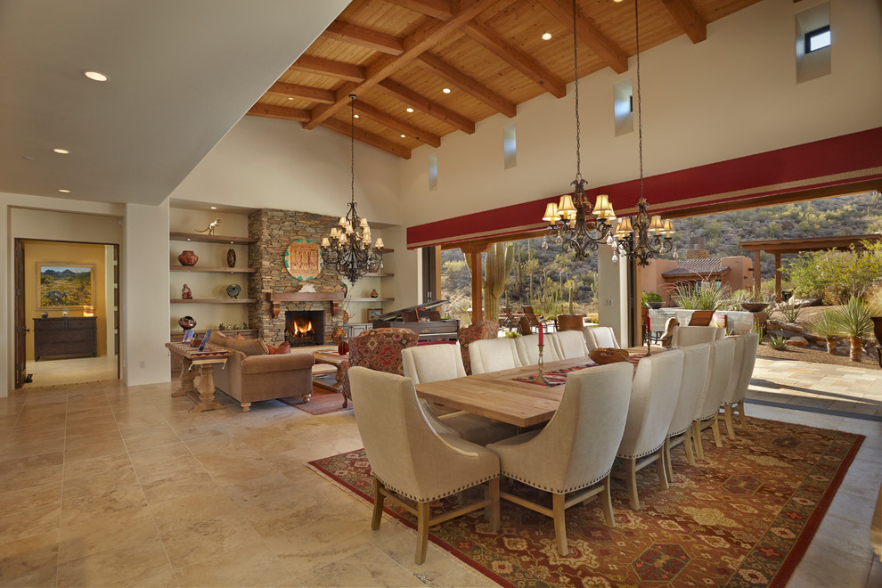 Foto di un'ampia sala da pranzo american style con pareti beige, pavimento in travertino, camino classico e cornice del camino in pietra