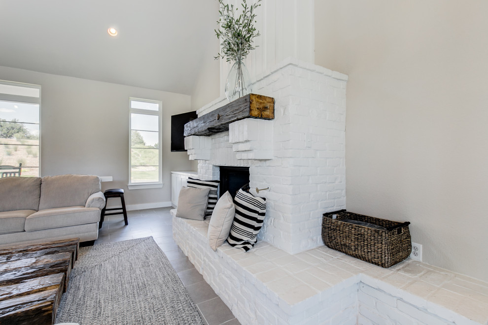 Стильный дизайн: открытая гостиная комната среднего размера в стиле рустика с серыми стенами, полом из керамической плитки, стандартным камином, фасадом камина из кирпича и серым полом - последний тренд