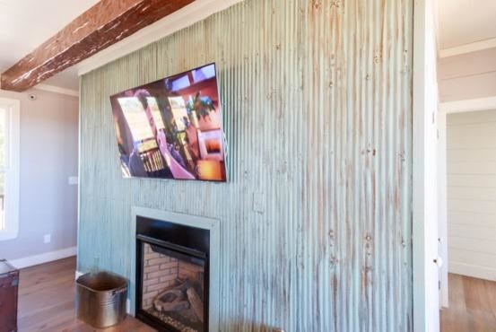 Пример оригинального дизайна: гостиная комната среднего размера в стиле кантри с серыми стенами, паркетным полом среднего тона, стандартным камином, фасадом камина из металла, телевизором на стене и коричневым полом
