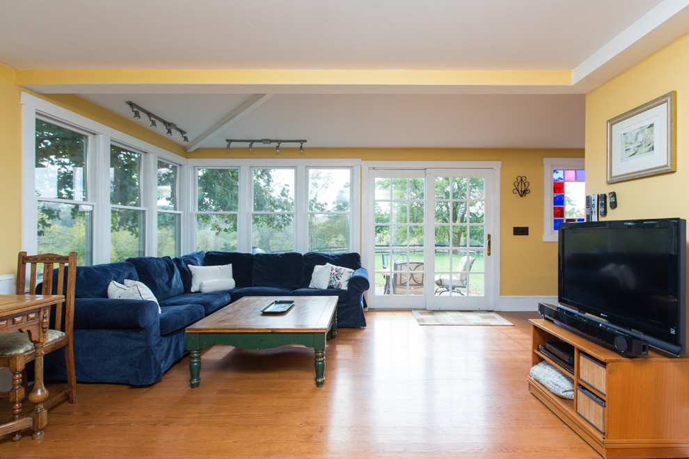 Esempio di un soggiorno country di medie dimensioni e aperto con pareti gialle, pavimento in legno massello medio e TV autoportante