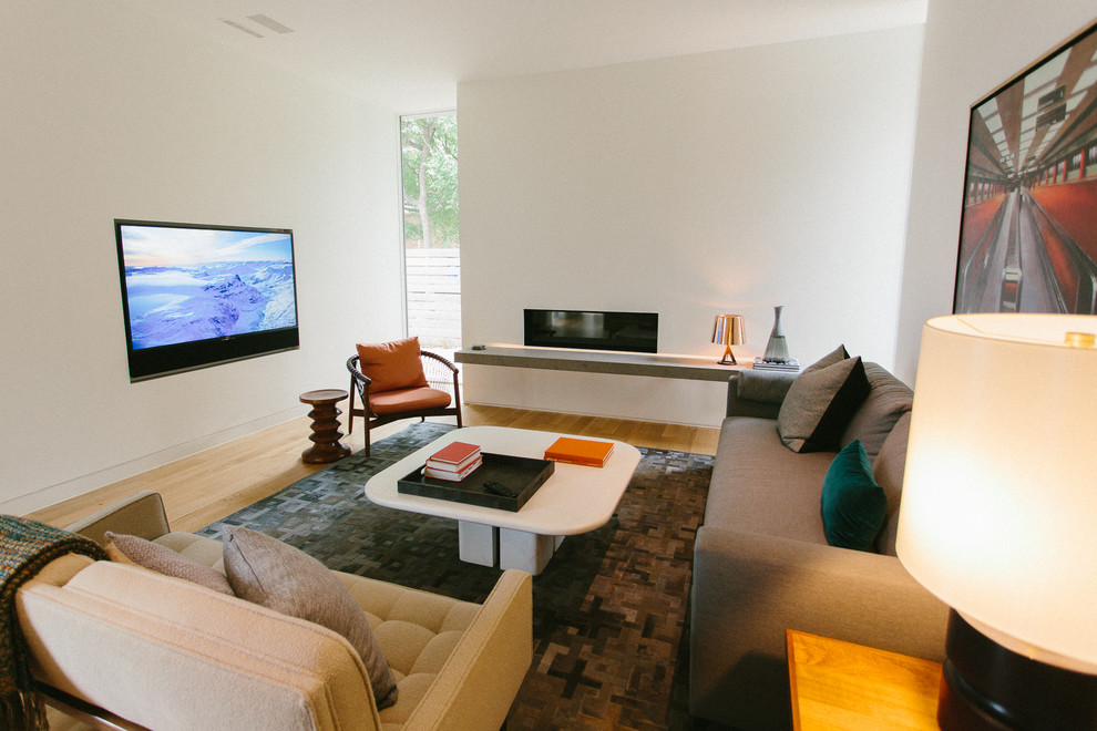 Bild på ett litet funkis separat vardagsrum, med ett finrum, vita väggar, ljust trägolv, en bred öppen spis, en spiselkrans i gips, en väggmonterad TV och brunt golv