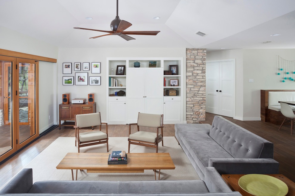 Foto di un soggiorno moderno aperto con pareti grigie, pavimento in gres porcellanato e TV nascosta