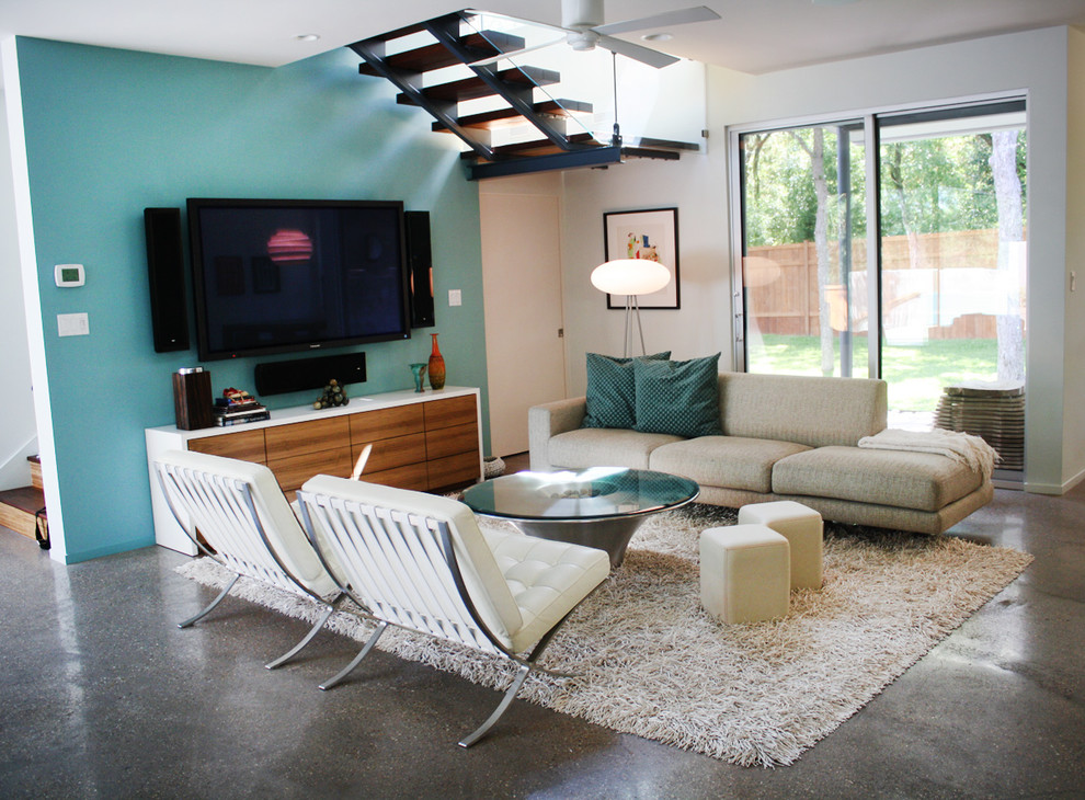 Ispirazione per un soggiorno minimalista di medie dimensioni e aperto con pareti blu, pavimento in cemento e TV a parete