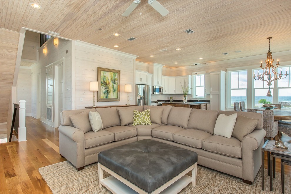 Idee per un grande soggiorno stile marino aperto con pareti beige, pavimento in legno massello medio e nessun camino