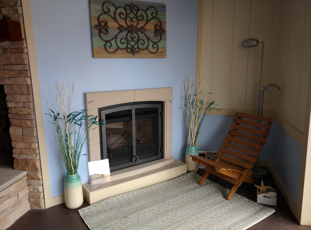 アトランタにある中くらいなビーチスタイルのおしゃれなリビング (青い壁、コンクリートの床、標準型暖炉、石材の暖炉まわり、茶色い床) の写真