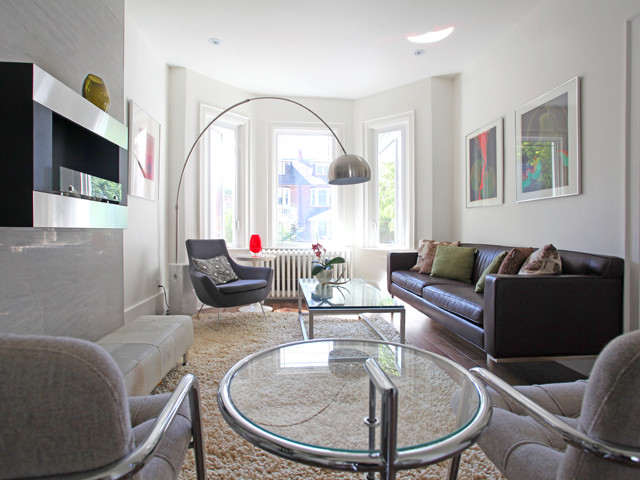 Großes, Fernseherloses, Abgetrenntes Modernes Wohnzimmer mit weißer Wandfarbe, braunem Holzboden, Hängekamin und gefliester Kaminumrandung in Toronto