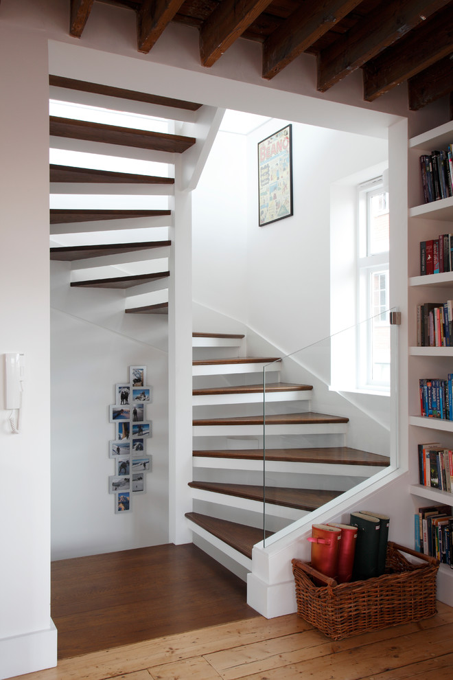 Réalisation d'un grand escalier sans contremarche hélicoïdal design avec des marches en bois et un mur en parement de brique.